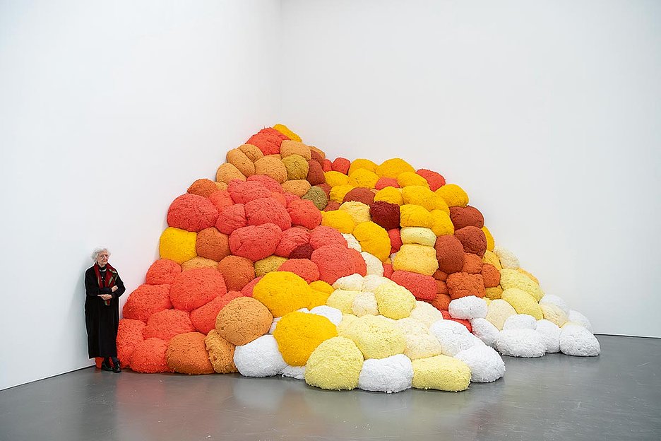 Sheila Hicks neben ihrer Arbeit, ­Saffron Sentinel, 2017, Eingefärbte Fasern Courtesy die Künstlerin, © VG Bild-Kunst, Bonn 2024, Foto: Katja Illner