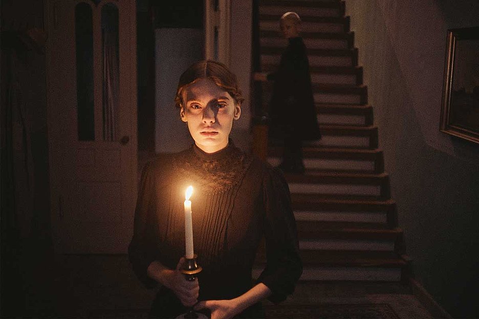© Neue Visionen Filmszene aus Mascha Schilinskis Film»In die Sonne schauen«: eine junge Frau steht mit einer brennenden Kerze in einem dunklen Treppenhaus