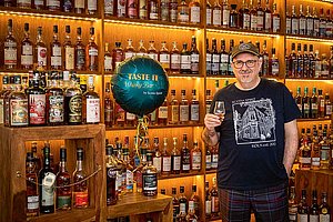 Peter Klas steht vor einem wandfüllenden Regal mit Scotch-Whisky-Flaschen in seiner Tasting-Bar "Scotia Spirit" im Friesenviertel