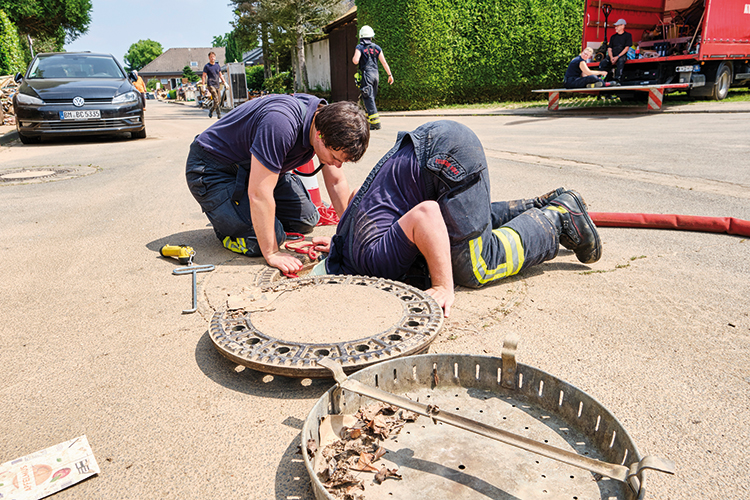 Foto: Thomas Schäkel / Stadtrevue Engel auf Rädern: Zwei Polizisten geben Tipps, welche Straßen für den ambulanten Pflegedienst zurzeit passierbar sind (oben). Zwei Helfer der Freiwilligen Feuerwehr Köln-Kalk prüfen die Kanalisation. Sie wollen einen vollgelaufenen Keller auspumpen